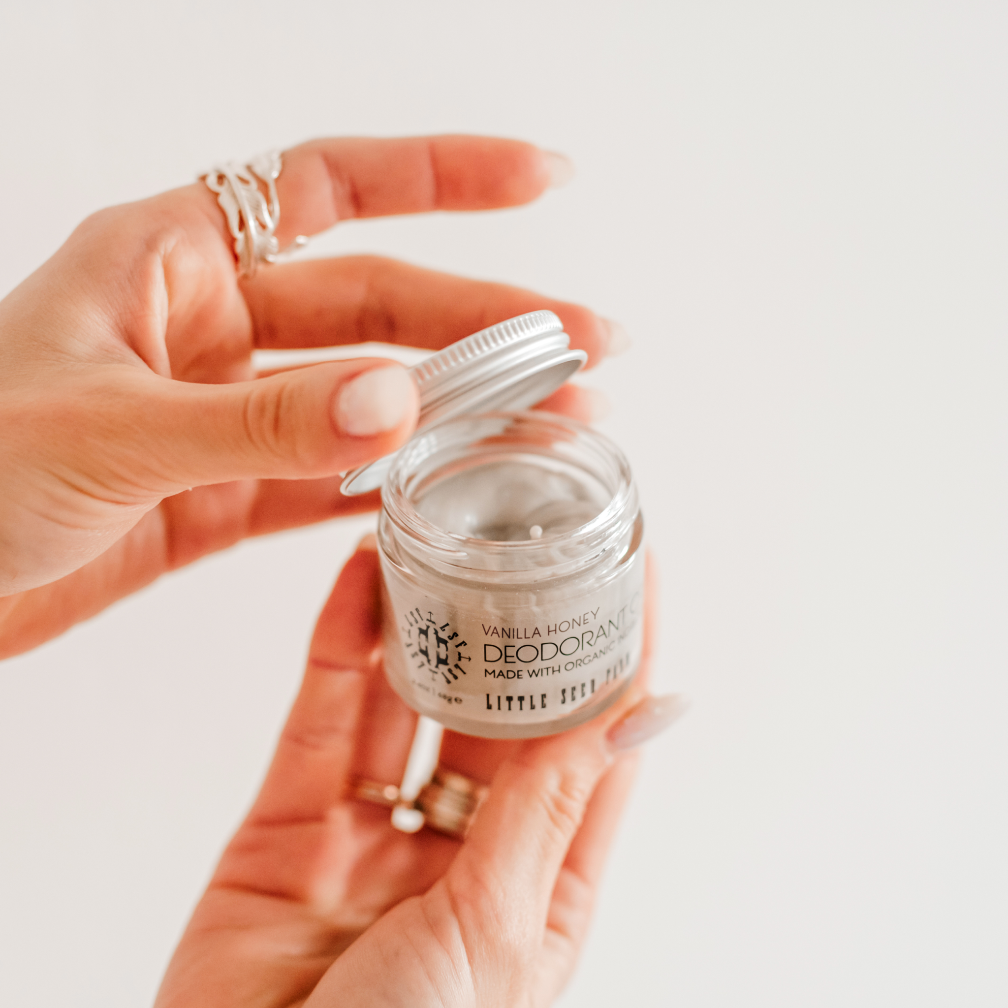Woman's hands holding an open jar of natural vanilla honey deodorant from Little Seed Farm