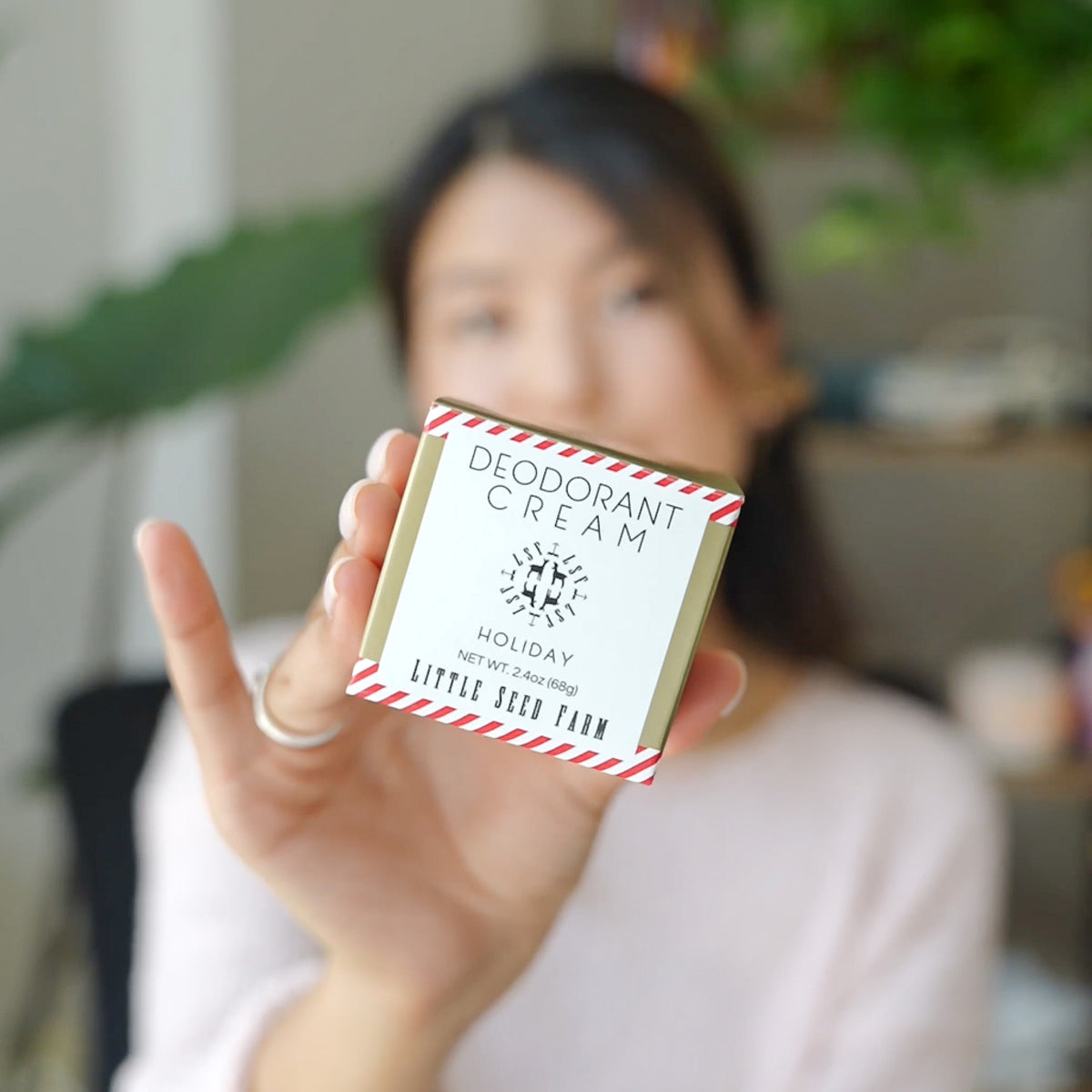 a woman holing a box of little seed farm holiday deodorant cream in front of her.