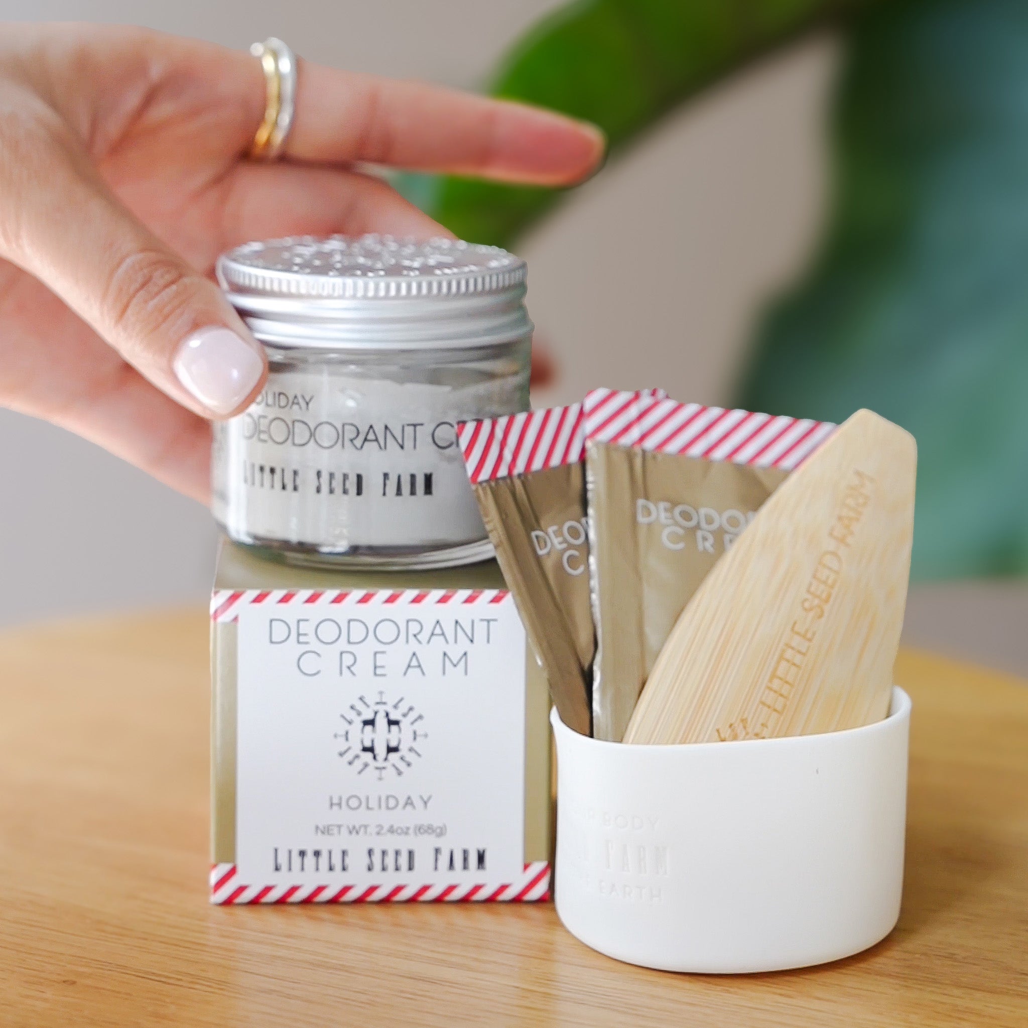 The little seed farm holiday deodorant, deodorant sample and the bamboo applicator sitting together on a table.