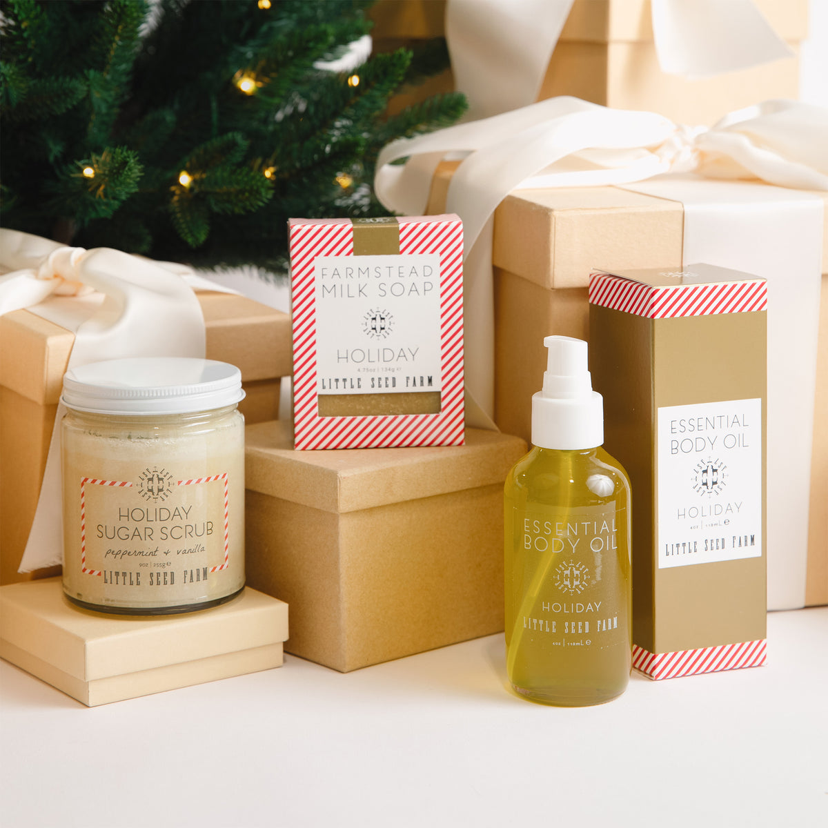 the little seed farm holiday sugar scrub, goats milk soap and 4 oz body oil sitting on gift boxes.