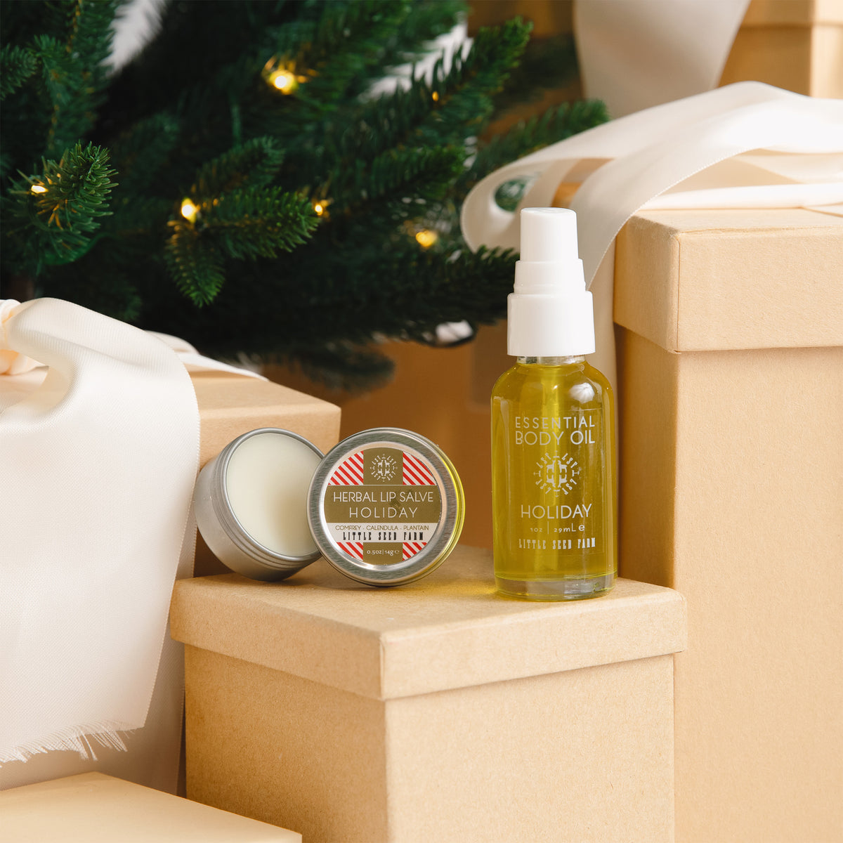 the little seed farm holiday body oil and holiday herbal lip salve sitting on gift boxes.