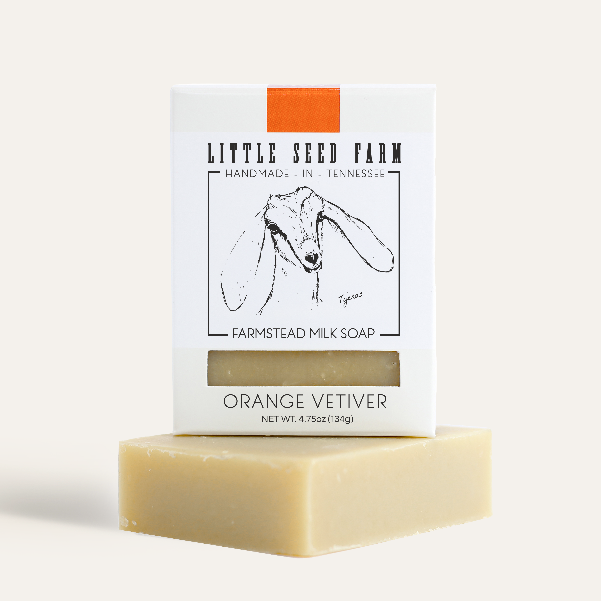 A bar of little seed farm orange vetiver goat's milk soap on a beige background.